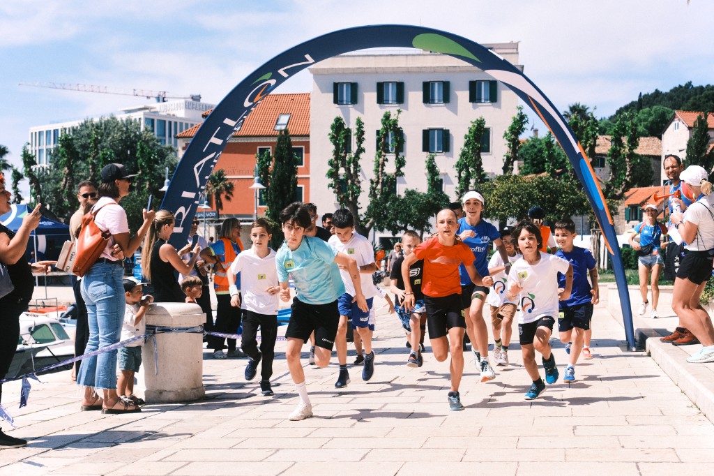 Kids racing under the triathlon arch on the seaside promenade